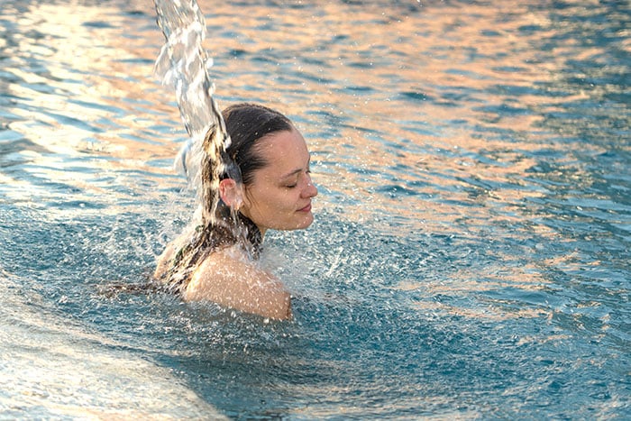 Frau im Wasser unter Wasserstrahl